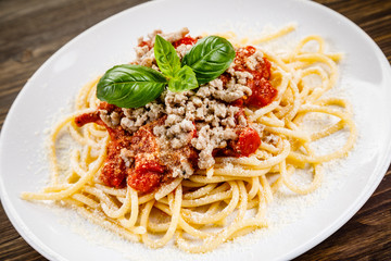 Pasta with meat and tomato sauce on wooden table