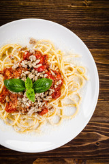 Pasta with meat and tomato sauce on wooden table