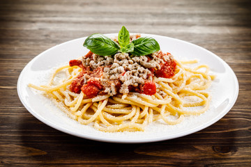 Pasta with meat and tomato sauce on wooden table