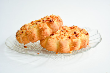two cookies, sprinkled with roasted peanuts, on a plate of clear glass on a light background