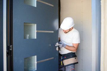 handsome young man installing a door in a new house construction site - obrazy, fototapety, plakaty