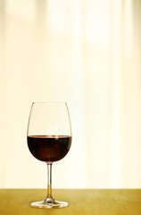 Single Red Wine in Bordeaux-shaped glass on Left Side of Copper Counter Top, with defocused Window and White Curtain, plain background, No decoration, Ambient Warm Day Lighting Studio image 1