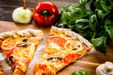 Slices of pizza and vegetables on wooden table