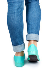 Female leg in jeans and sneakers isolated on white background