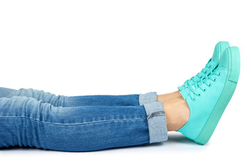 Female leg in jeans and sneakers isolated on white background