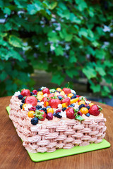Fototapeta na wymiar Delicious birthday or wedding cake with fresh fruits and berries on board outdoors, copy space. Cake decorated with strawberry, raspberry, blackberry, blueberry, apricot and peach