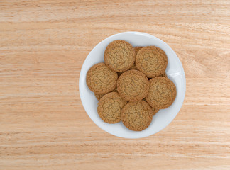 Top view of apple pie crust cookies on a white plate atop a wood table.