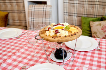 Wooden board with assortment of delicious cheese, grapes and honey on dinner table. Various types of cheese. Cheese plate with Dorblu, Parmesan, Brie, Camembert and Roquefort. Cheese Platter
