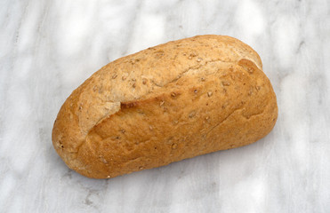 Small whole wheat bread loaf on a gray marble counter top.