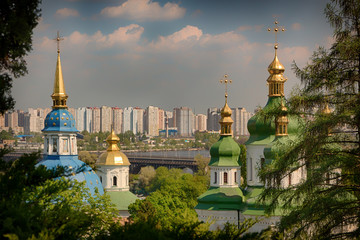 Fototapeta na wymiar Dome of one of the cathedrals on the territory of Kiev Pechersk Lavra. On the background of the city in the morning fog, and the lantern in the foreground