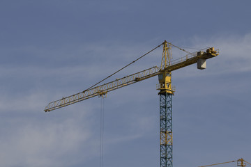 tower crane against the blue sky, the process of building a multi-storey building