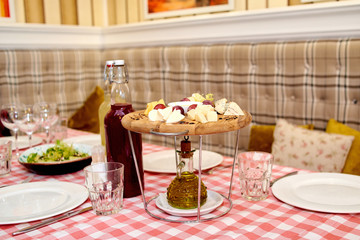 Wooden board with assortment of delicious cheese, grapes and honey on dinner table. Various types of cheese. Cheese plate with Dorblu, Parmesan, Brie, Camembert and Roquefort. Cheese Platter