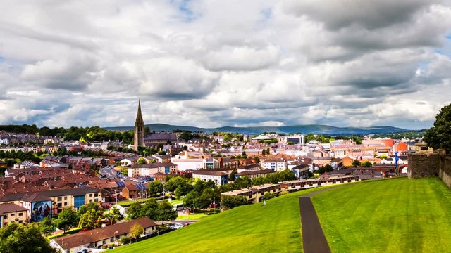 Derry, North Ireland. Aerial view of Derry Londonderry city center in Northern Ireland, UK. Sunny day with cloudy sky, city walls and historical buildings. Time-lapse, zoom in