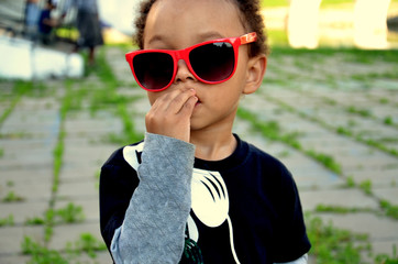 Portrait of cute mixed african american boy in funny sunglases. Summer in the city.