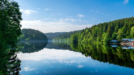 Fototapeta na wymiar Spiegelung der Bäume und Wolken im See im bayerischen Wald