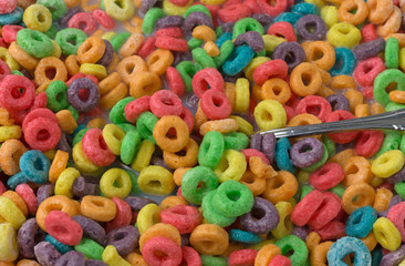 Fototapeta na wymiar Close view of sugar coated fruity flavored cereal with milk and a spoon.