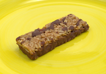 Chocolate with nuts granola bar on a bright yellow plate.