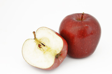 Media manzana roja, cortada por la mitad, al lado de manzana roja entera, sobre fondo blanco. 