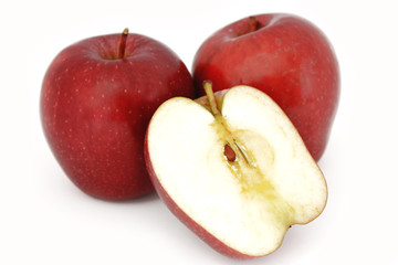Dos manzanas rojas enteras, sujetan media manzana, partida a la mitad, sobre f