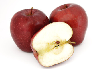 Naklejka na ściany i meble Dos manzanas rojas enteras, sujetan media manzana, partida a la mitad, sobre fondo blanco.
