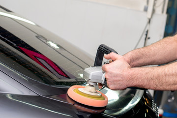 A man polishes a black car with a polisher