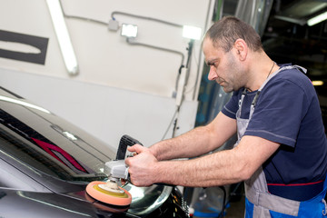 A man polishes a black car with a polisher