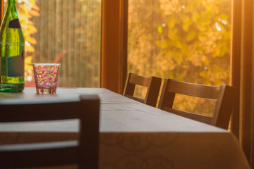 A table with chairs stands in front of a window in which the sun shines, home architecture, home comfort, artistic background