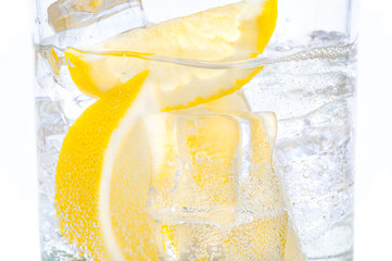 In a glass with cubes of melting ice slices of a juicy lemon.