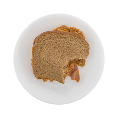 Bitten curry flavored tuna sandwich on a plate isolated on a white background.