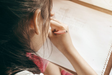 A girl is drawing.A kid is doing homework.