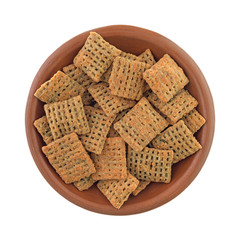 Top view of a bowl of cheddar cheese wheat square crisps isolated on a white background.