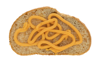 Canned cheese on a slice of wheat bread isolated on a white background.