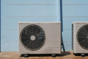 Air Conditioner Condenser Unit at a Blue Color Painted Concrete Wall