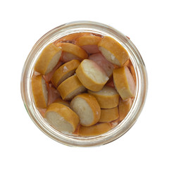 Top view of an open glass jar filled with smoked sausage slices isolated on a white background.