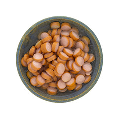 Top view of an old stoneware bowl filled with smoked sausage slices isolated on a white background.