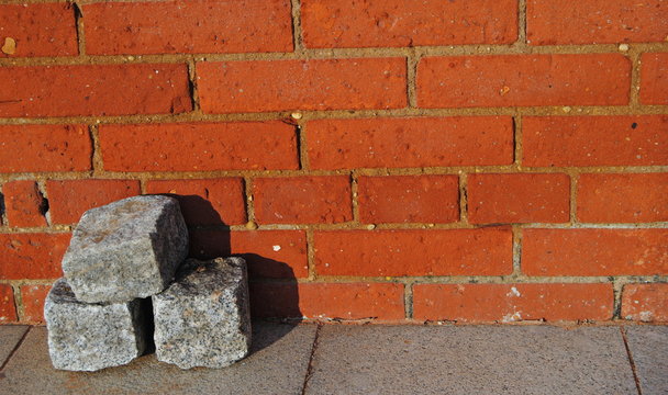 Tr&ecirc;s paralelos empilhados no ch&atilde;o com uma parede de tijolos por tr&aacute;s