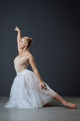 Fototapeta premium Young perspective ballerina holding up hand standing on her knee.