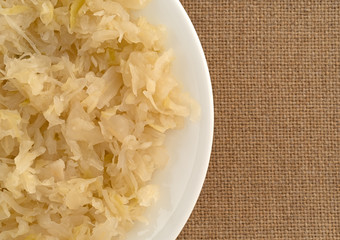 Top close view of sauerkraut on a white plate atop a tablecloth.