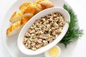 fish liver salad in an oval bowl served with white bread, egg, and dill