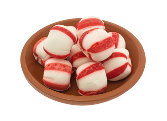 Peppermint balls in a red clay bowl isolated on a white background.