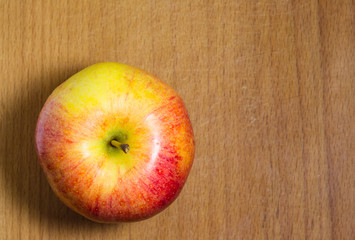 Naklejka na ściany i meble A yellow-red apple on a wooden table