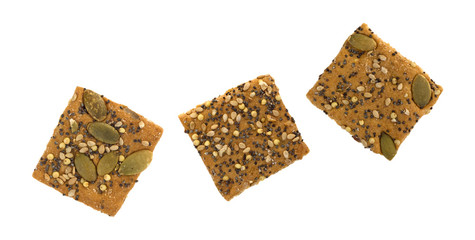 Top view of three whole wheat seeded crackers on a white background.