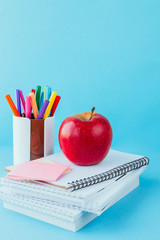 School and office supplies on classroom table in front of blue blackboard. View with copy space concept back to school