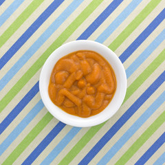 Top view of organic pumpkin and carrot baby food on a striped tablecloth.