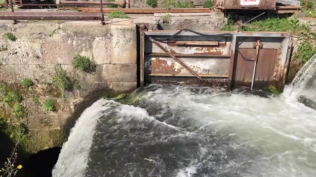Time lapse of a waterfall with many foam in a rusty lock in a sunny day.