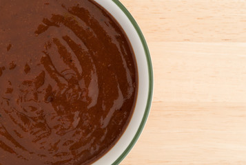 Top close view of pulled pork starter sauce in a bowl on a wood table.
