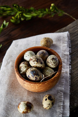Bowl with eggs quail, eggs on a homespun napkin, boxwood on wooden background, close-up, selective focus