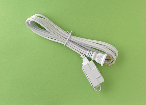 New white extension cord on a green paper background.