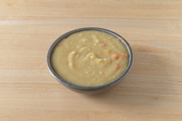 Home style potato soup in a stoneware bowl on a table illuminated with natural light.