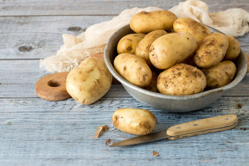 Young early potatoes in an old aluminum bowl on a wooden table.  © elizaveta66